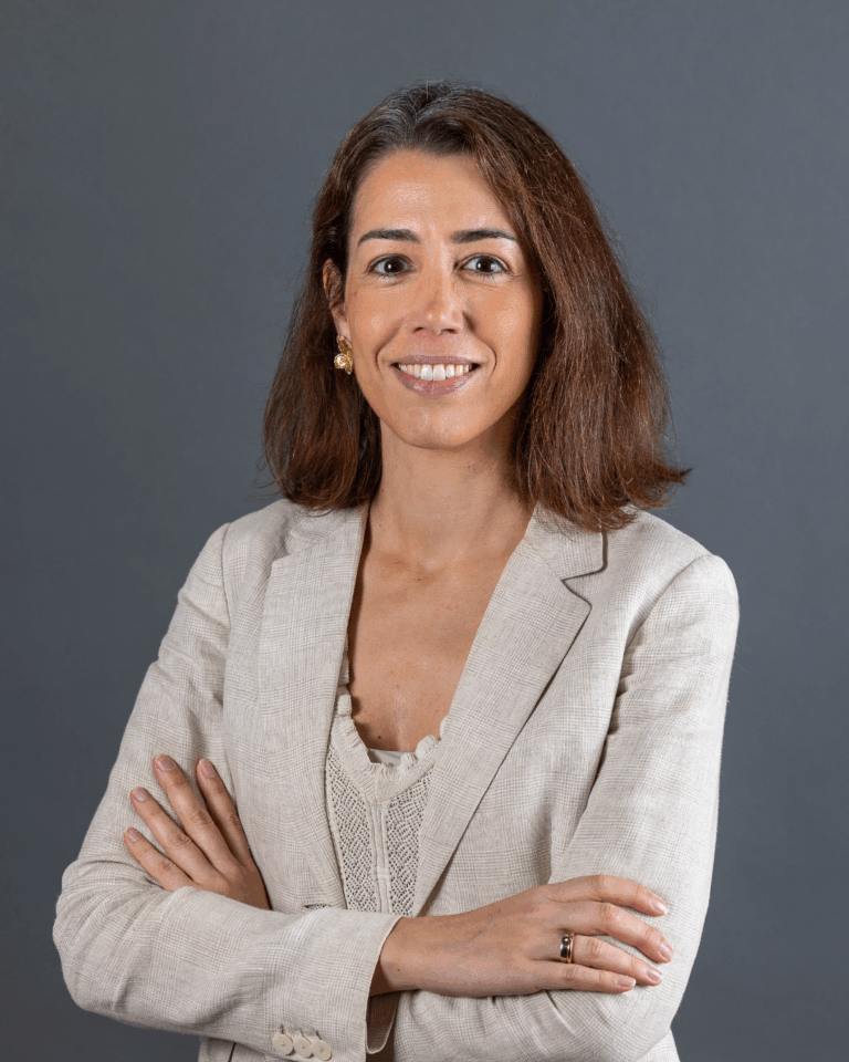 Mulher com blazer claro e braços cruzados.