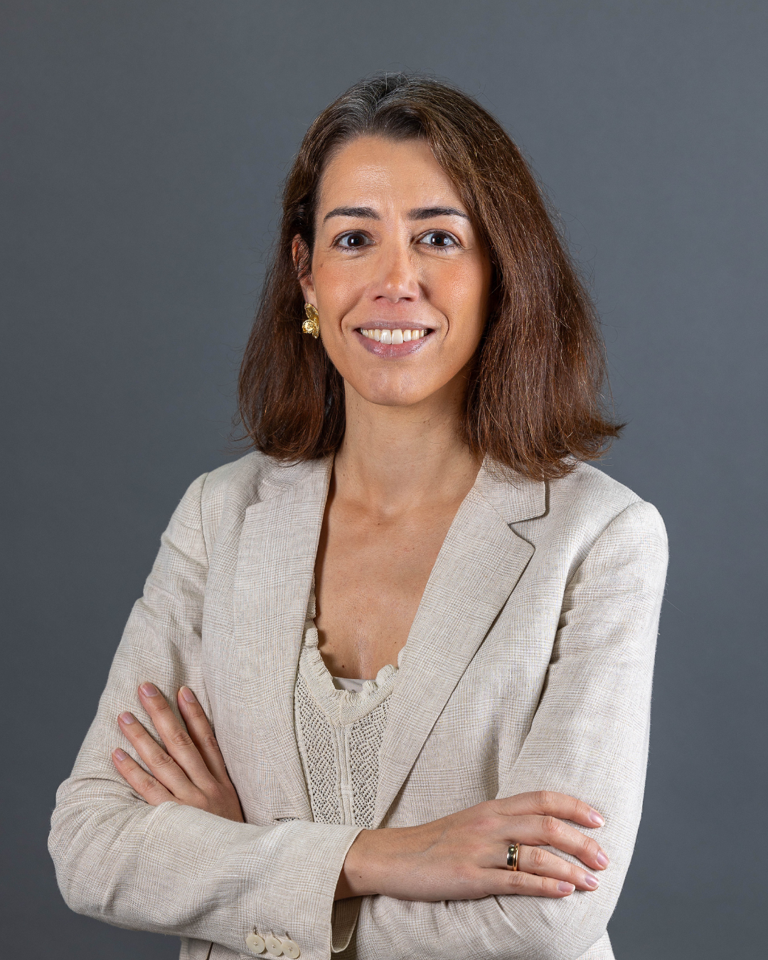 Mulher com blazer claro e braços cruzados.