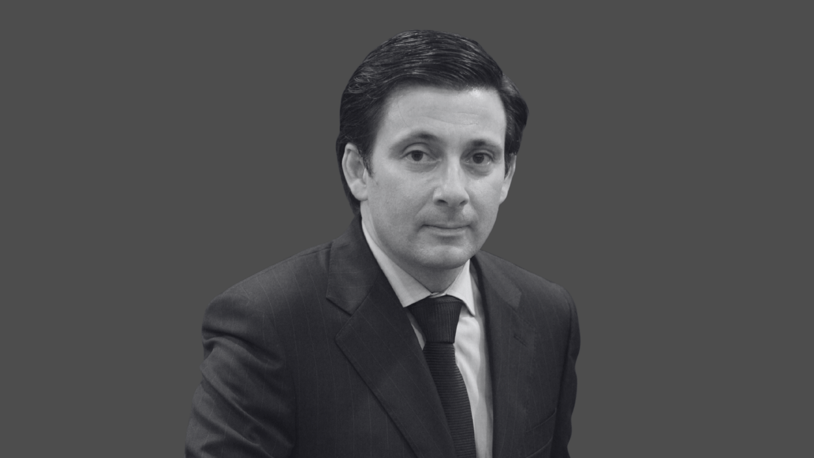 Homem de terno em fundo cinza.