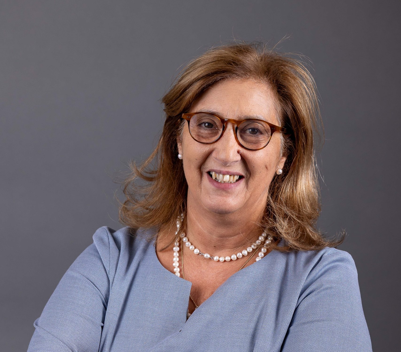 Mulher sorridente com braços cruzados.