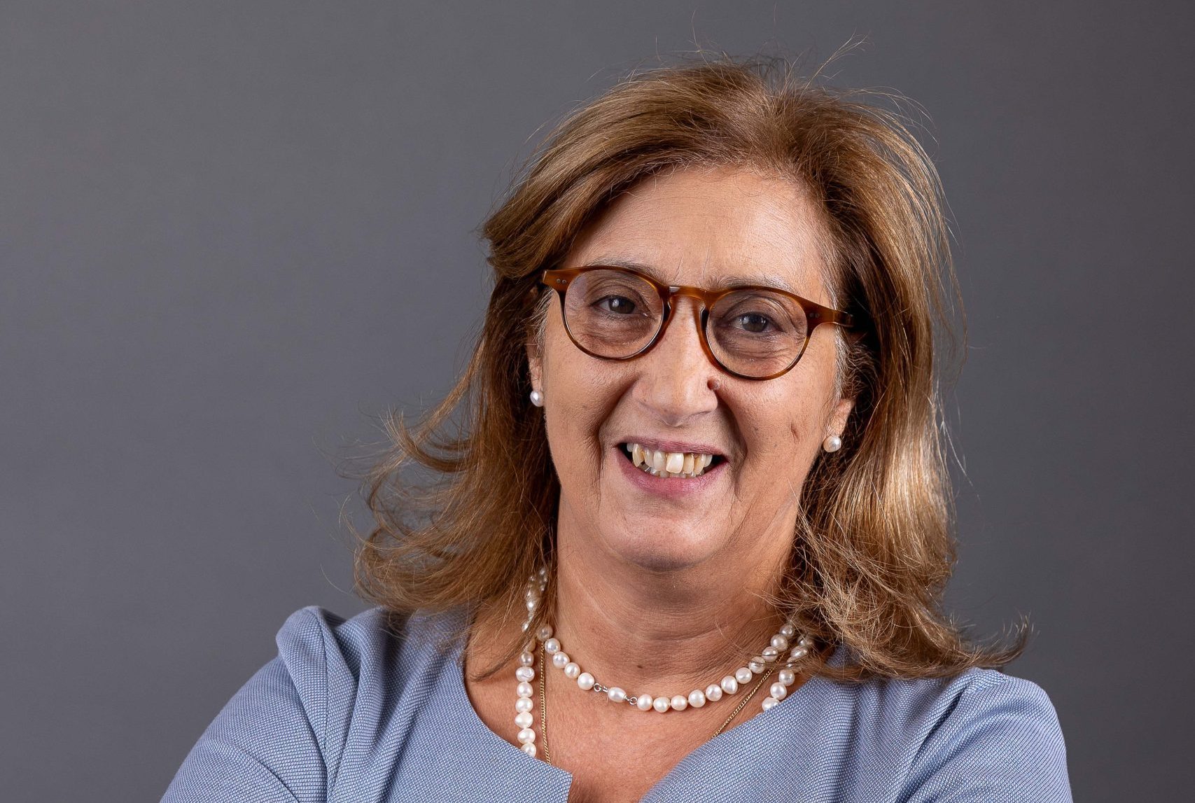Mulher sorridente com braços cruzados.